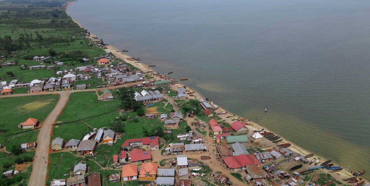 An aerial view of Kasensero, a lakeshore village on Lake Victoria, with houses and fishing boats lining the shore.